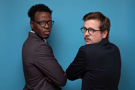 Two african and caucasian men in suit with glasses turning back being angry