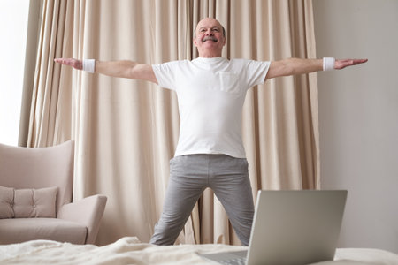 Portrait of a smiling senior man in sportswear standing at yoga asanaの写真素材