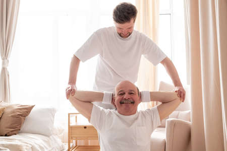 Male yoga trainer helps to senior man to do asana correctly.の写真素材