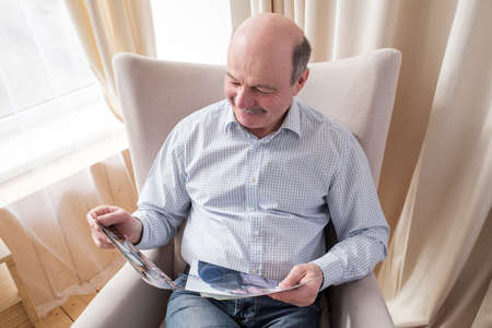 Senior man wathcing photos of his family smiling