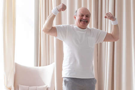 Senior man showing muscle being proud with his health
