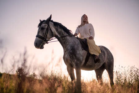 young blonde woman walking with her horseの写真素材