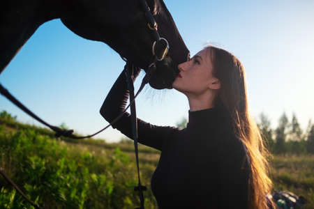 Young beautiful woman taking care of her horse hugging it.の写真素材