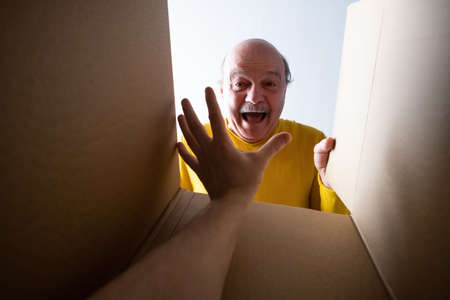 man unpacking, opening carton box and looking inside. Somebody attack him.の写真素材