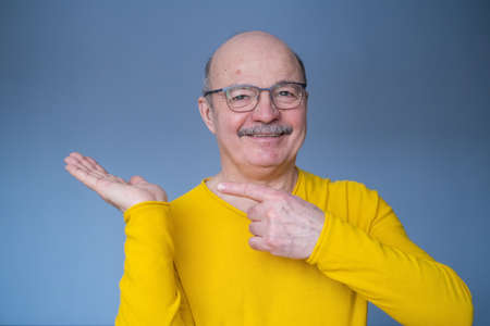 Senior man pointing with index finger to important informationの写真素材
