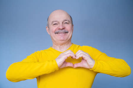 Senior man with smile showing heart symbol with his handsの写真素材