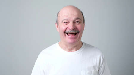 Handsome senior man in white t-shirt laughing. positive facial emotion. good joke conceptの写真素材