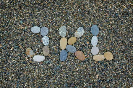 alphabet letters jkl made from stones in sand on beachの写真素材
