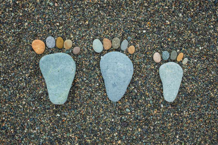 Happy family feet. Stone arranged like a footprint on the beachの写真素材