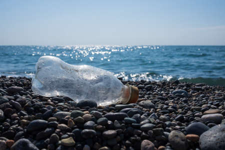 Empty used plastic bottle on beach background. environmental pollution concept