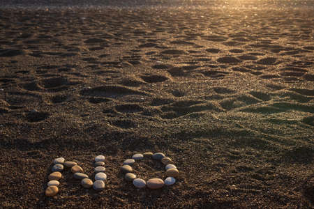Word No made from stones on sandy beachの写真素材