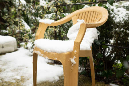 snow on plastic chair in small yard. Unexpected frosts in spring in Georgiaの写真素材