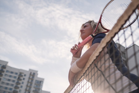 Mature woman resting after playing tennis outside.の写真素材