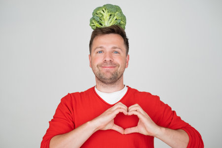 Man holding green fresh broccoli showing heart gestureの写真素材
