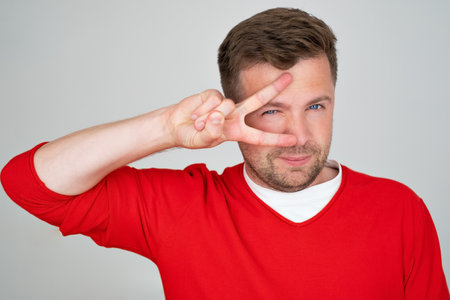 Caucasian mature man smiling showing fingers doing victory sign. number two.の写真素材