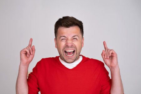 Young smiling attractive manpointing index finger up.