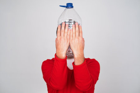 Recycle waste management concept. Man hiding behind an empty water bottle.