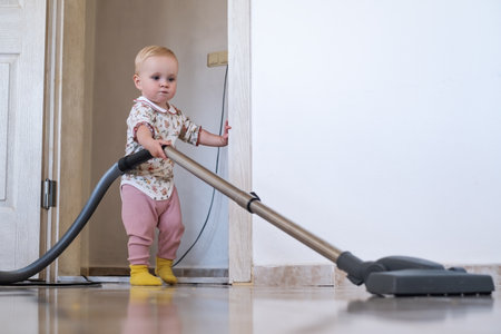 Baby girl cleaning the carpet with vacuum cleanerの写真素材