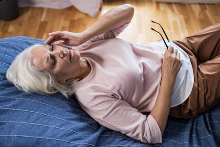 Senior woman suffering from a headache resting at home on sofaの写真素材