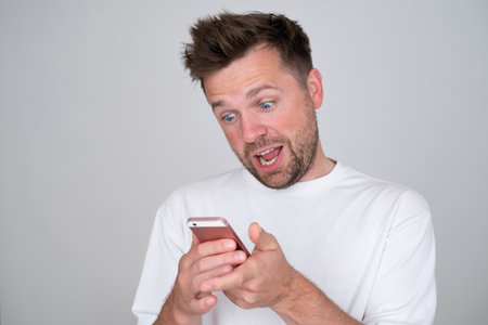 man looking at screen of smart phone, smiling nicely while chatting with friendの写真素材