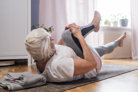Elderly woman doing pilates on mat at homeの写真素材