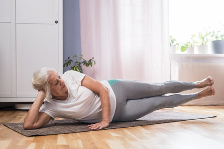 Elderly woman doing pilates on mat at homeの写真素材