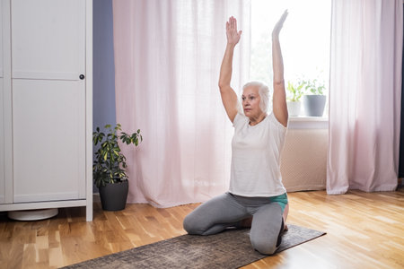 Elderly woman doing pilates on mat at homeの写真素材