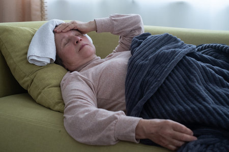 A sick old woman laying down in bed and having migraine.の写真素材