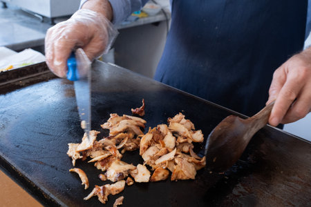 a chef cutting meat with a knife for a street food doner kebab or shawarma.