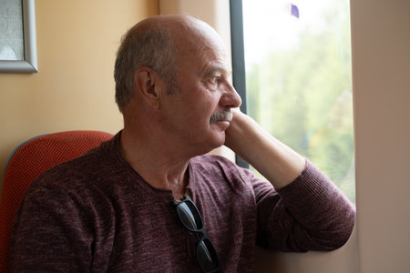 elderly man with mustache riding on train and dozing