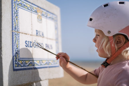 Little Girl in a Bike Helmet Learning to Read a Street Signの写真素材