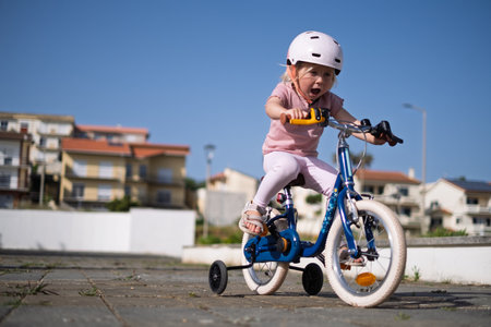 European Girl Riding a Bike in a Helmet, Learning to Ride on Her Ownの写真素材