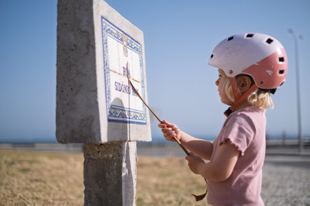 Little Girl in a Bike Helmet Learning to Read a Street Signの写真素材