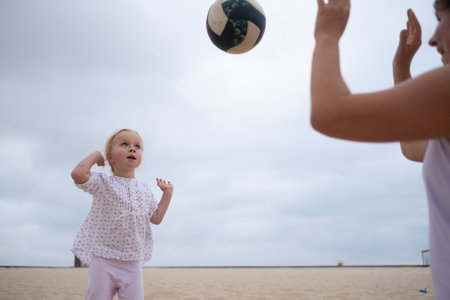 Mother teaching her 4-year-old daughter to play volleyball on the beachの写真素材