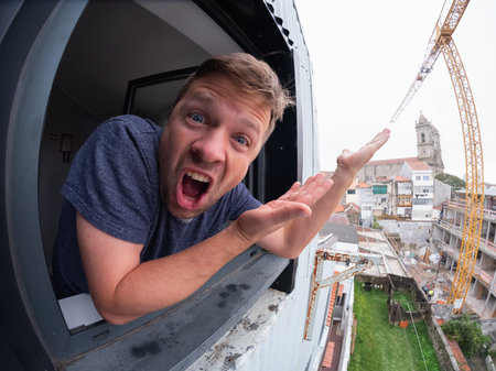 Man leaning out of the window pointing at bad weatherの写真素材