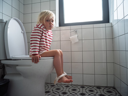 Little 4 year old girl sitting on the toilet during potty training at homeの写真素材