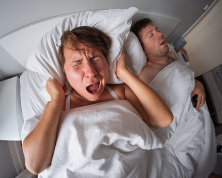 Woman covering her ears because her husband is snoring loudlyの写真素材