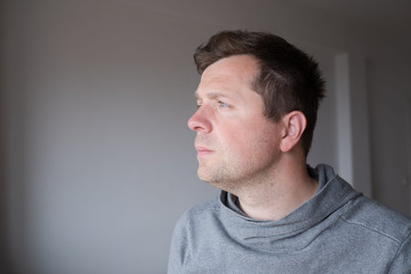 Thoughtful young man with illuminated face looking away and dreaming about the futureの写真素材