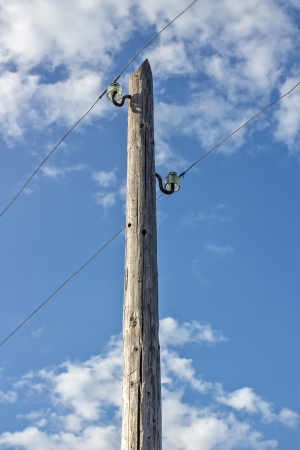 Old wooden electric pole against the blue sky and cloudsの写真素材