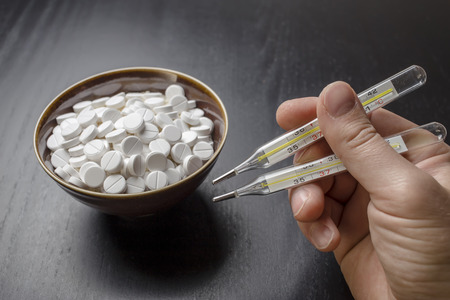man is going to eat the drug tablets in bowl and holds two medical thermometer like chopsticksの写真素材