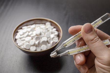 man is going to eat the drug tablets in bowl and holds two medical thermometer like chopsticksの写真素材