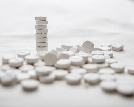 handful of medicinal drugs in the form of tablets on white tableの写真素材