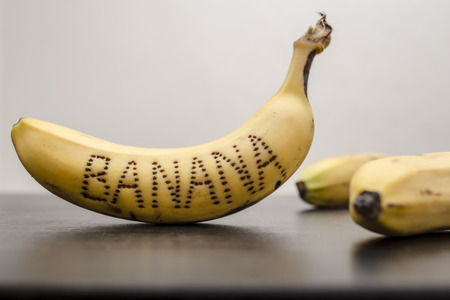bananas on the table, on the peel of one of them is written the word "banana"の写真素材