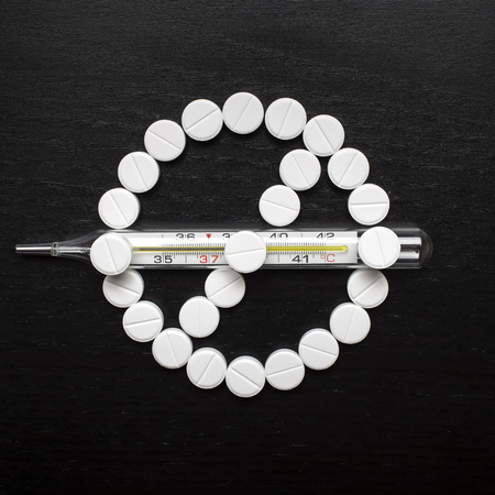 prohibiting sign made from medicinal tablets crosses medical thermometer with high temperatureの写真素材