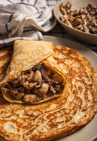 Russian traditional pancakes stuffed with fried chicken with mushrooms lie on a plateの写真素材