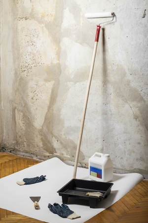 Tools for painting (roller, brush, gloves, paint), located at the wall and ready for repair in the roomの写真素材