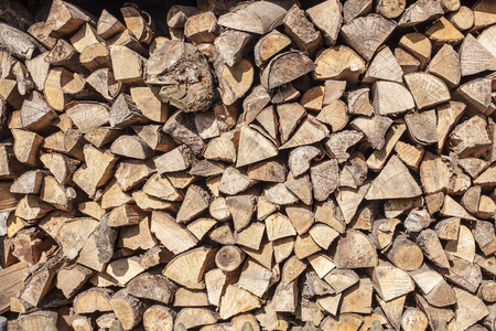 firewood stacked in a woodpile in the courtyard, lit by sunlightの写真素材