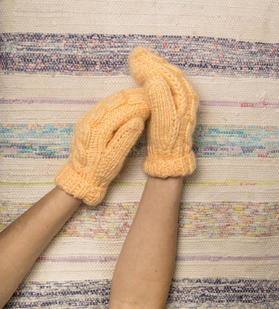 female hands in woolen knitted mittens of peach colorの写真素材