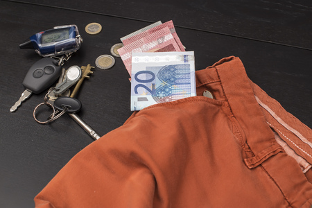 euro paper money and coins fell out of his pocket on a black table on which lay a bunch of house keys and carの写真素材