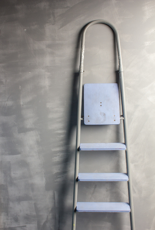 repair in an apartment by using a stepladder which stands leaning on painted gray wallの写真素材